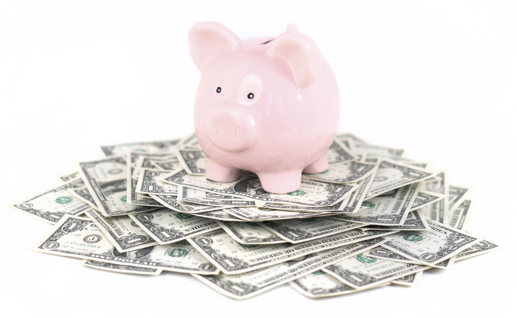 photo of piggy bank on top of a pile of money